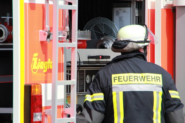 Bild vergr&ouml;&szlig;ern: Ein Feuerwehrmann von Hinten vor einem Rüstwagen
