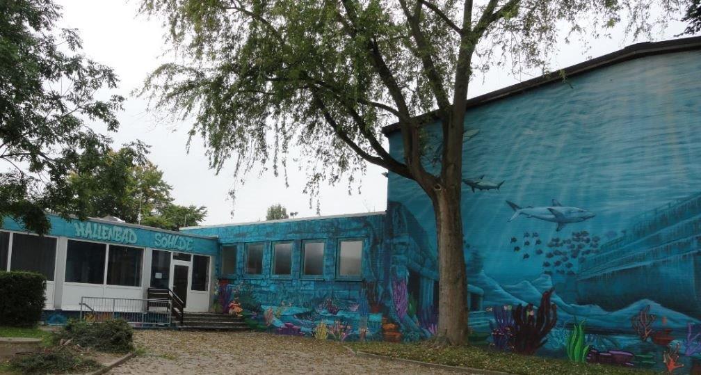 Eingangsseite der Kleinschwimmhalle, an den Wänden befindet sich ein Graffiti mit Unterwassermotiv